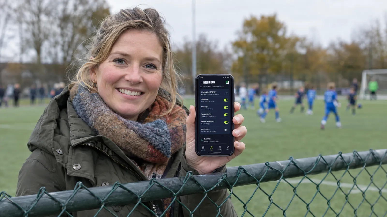 Ouder langs het hek toont de meldingeninstellingen van Basiself op haar telefoon